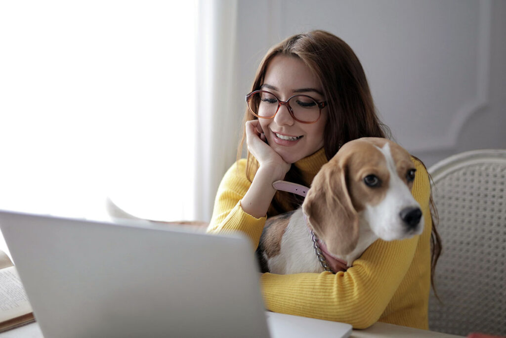 image of woman holding her dog while using laptop