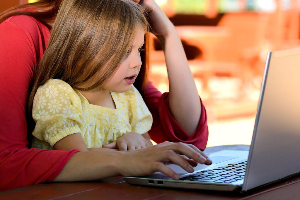 photo of a girl and her mother using a laptop